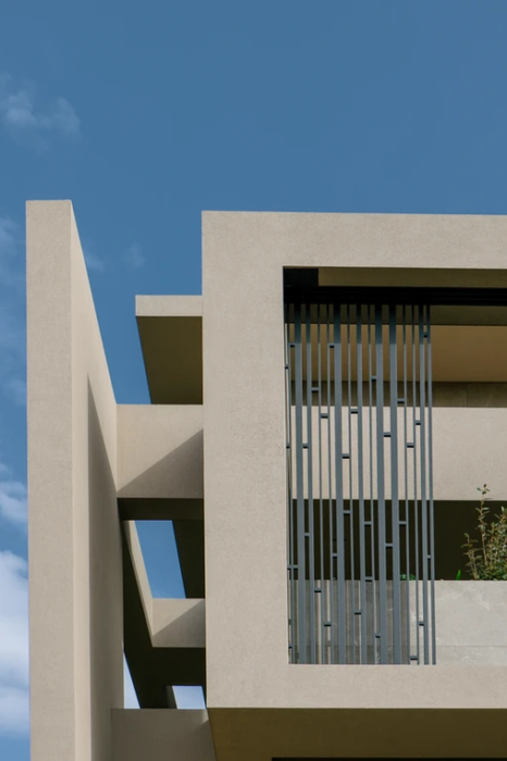 Λεπτομέρεια σύγχρονης facade κατοικίας με κάθετες μεταλλικές λάμες σκίασης και frameless ανοίγματα